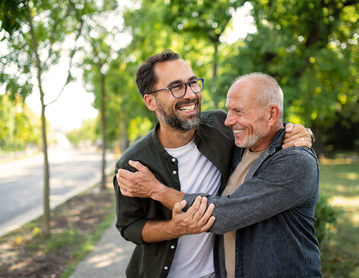 Ein Vater und sein Sohn laufen glücklich Arm in Arm an einem sonnigen Tag auf einem Gehweg