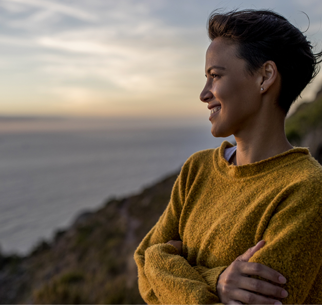 Frau die am Meer steht und in die Weite blickt