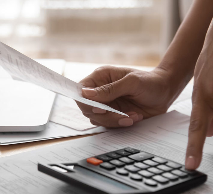 Close-Up image of someone holding a letter and using their calculator.