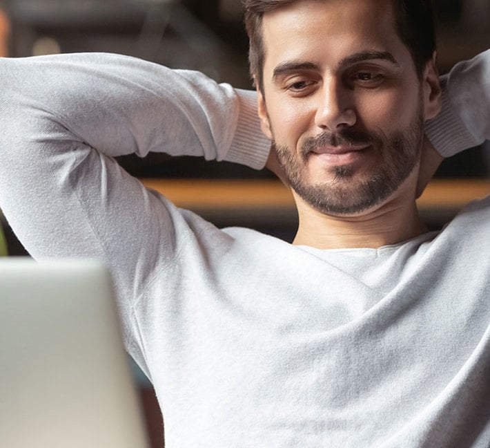 image of a man leaning back on his sofa, hands crossed behind his head.